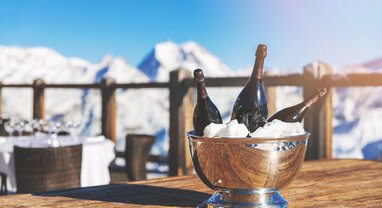 Bottle of wine on ice on outdoor terrace table with mountains in background
