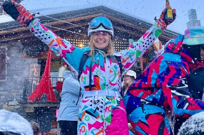 Girl in bright coloured ski gear dancing on table at Folie Douce