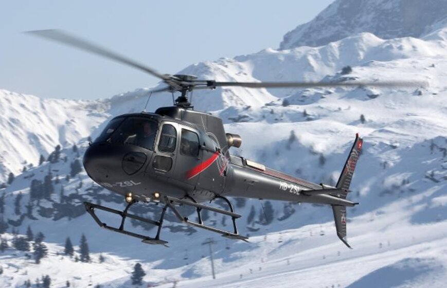 Grey and red helicopter flying in mountains