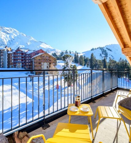 View of piste from balcony in Chalet Misha with yellow table and chairs