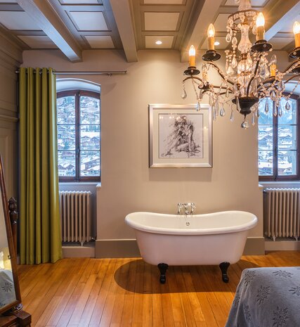 Freestanding bath in elegant bedroom with chandelier and snowy views in Chalet Manoir in Morzine 