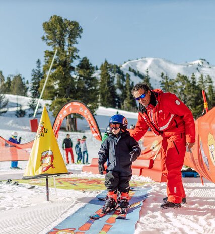 Young boy skier on beginner area outside Bear Lodge in Arc 1950 with ESF ski instructor