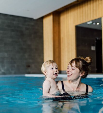 Smiling mother with young child in Bear Lodge indoor swimming pool in Les Arcs