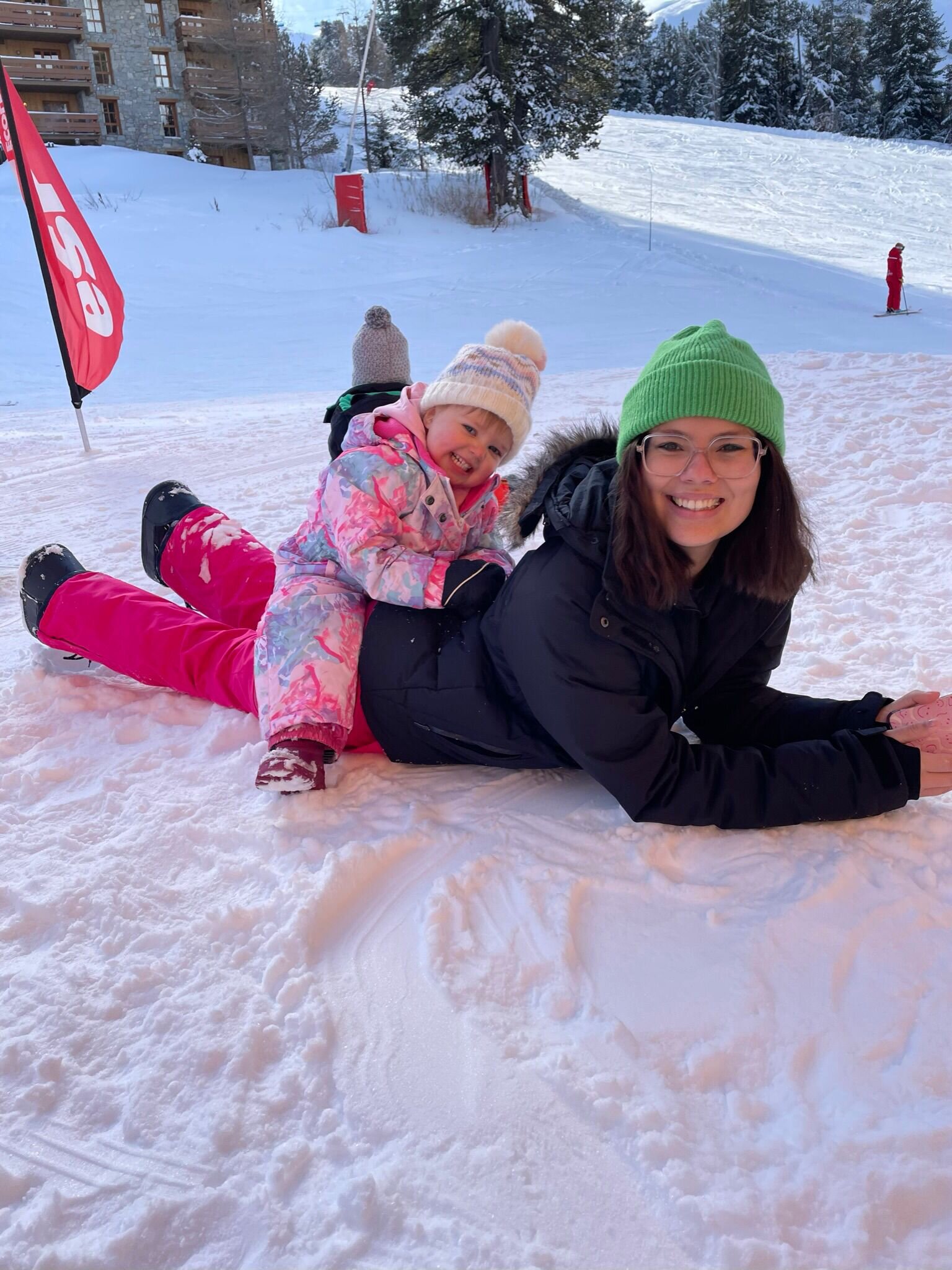 Private ski nanny with toddler, laying on the piste in Arc 1950