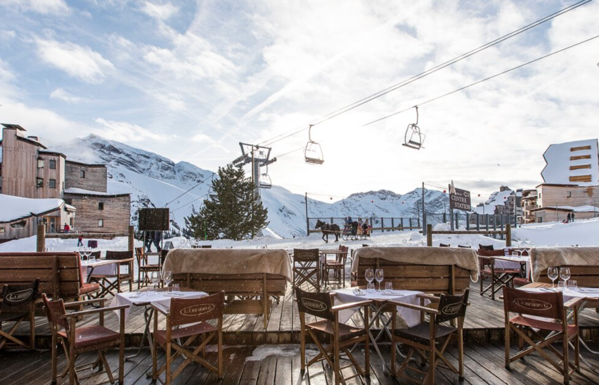 Restaurant terrace next to chairlift with warm blankets draped on benches