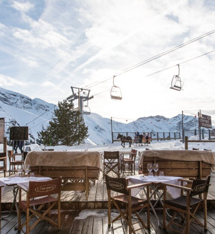 Outdoor seating area of La Reserve restaurant in Avoriaz with chairlift and horse drawn sleigh in background