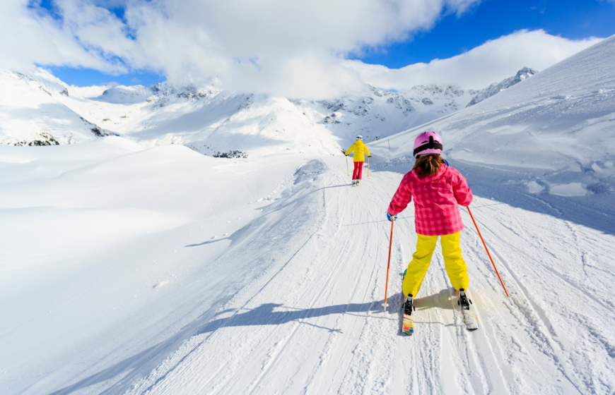 Young girl skiing behind mother