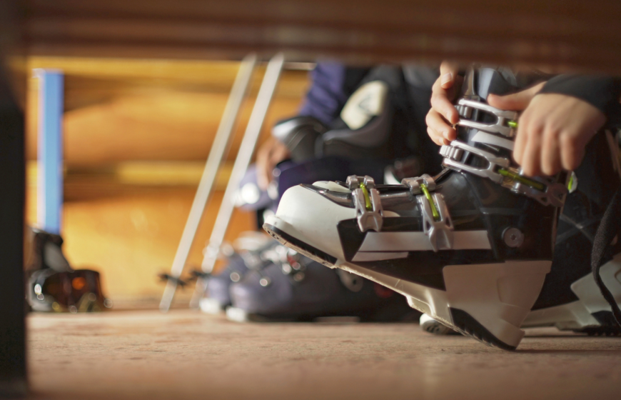 Person doing up ski boots in ski boot room