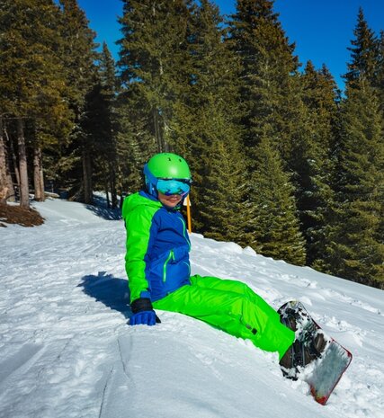 Young boy with snowboard sitting on snow