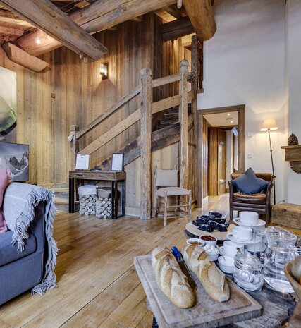 Cosy living area with sofa and open fire and afternoon tea laid out in Farmhouse ski chalet in Val d'Isere