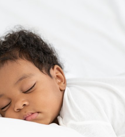 Afro-carribean baby sleeping on bed