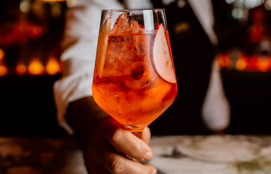 Closeup of Aperol Spritz being served by bar man in elegant bar