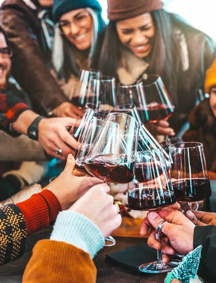 Friends clinking red wine glasses together at outdoor bar