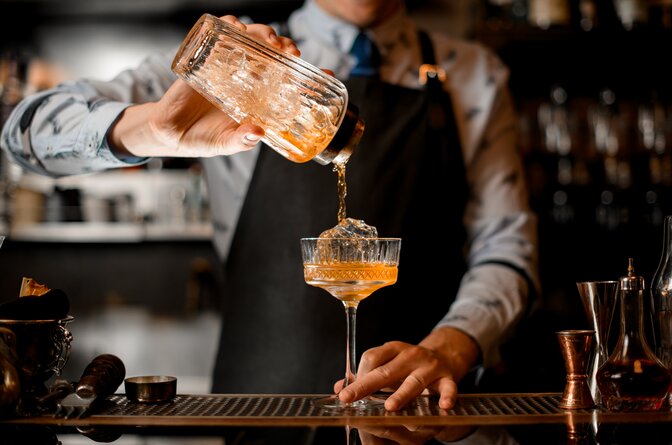 Orange cocktail being poured by barman