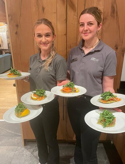 Two smiling VIP SKI chalet hosts holding salmon starters