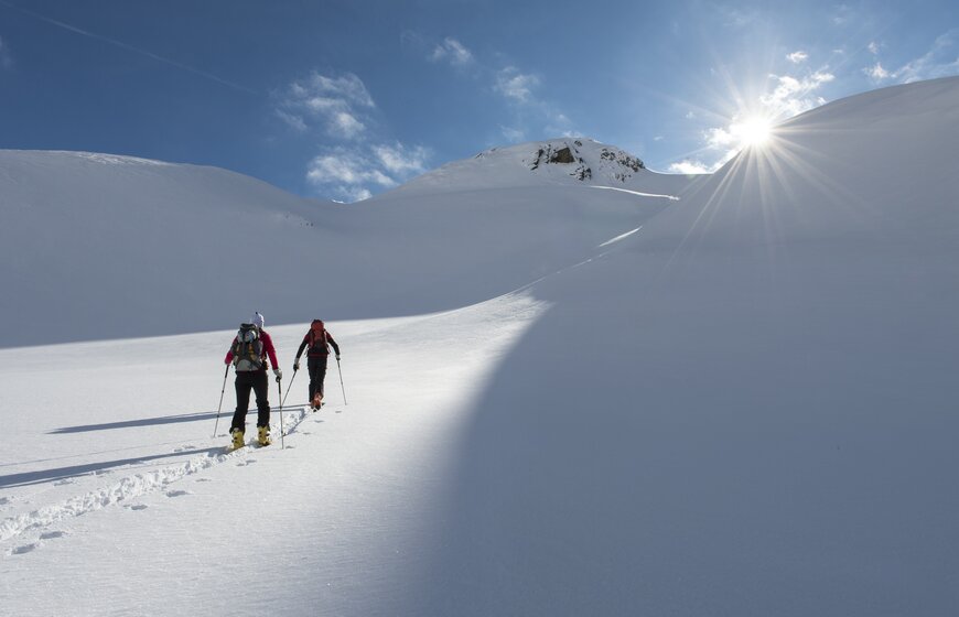 Two people ski touring up untracked slope