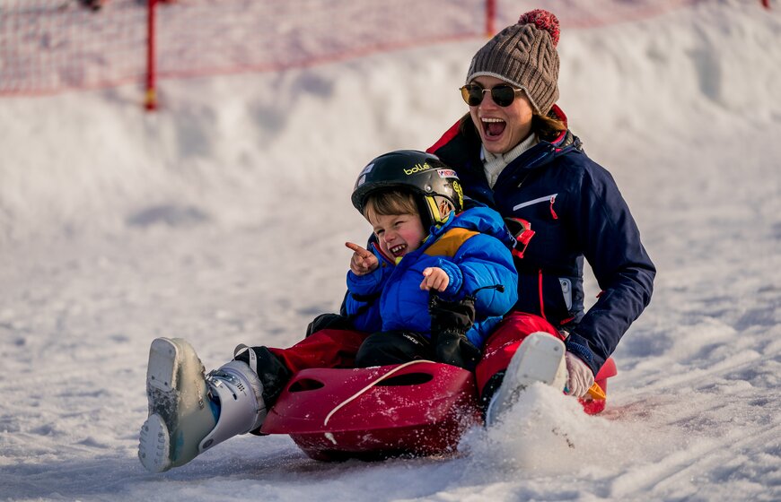 Smiling mother and son sledging together