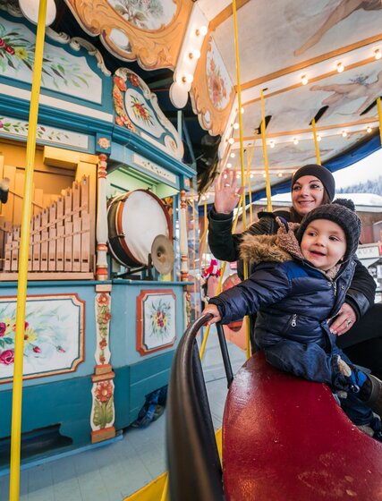 Mother and son on traditional carousel in Les Gets