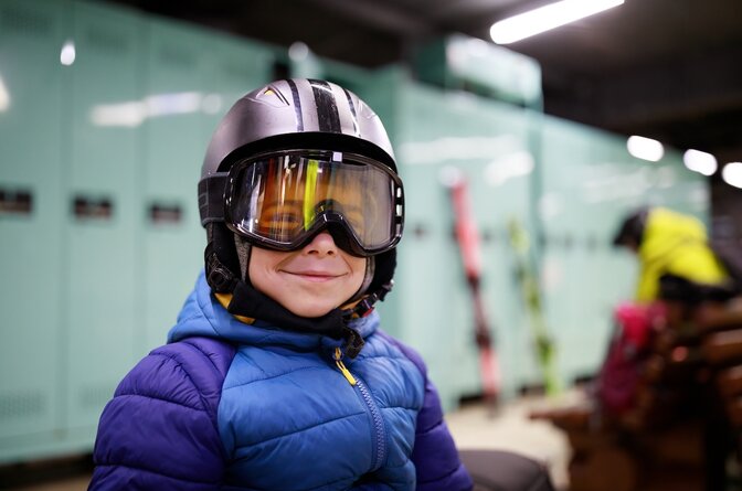 Smiling young boy wearing ski helmet and goggles in ski locker room