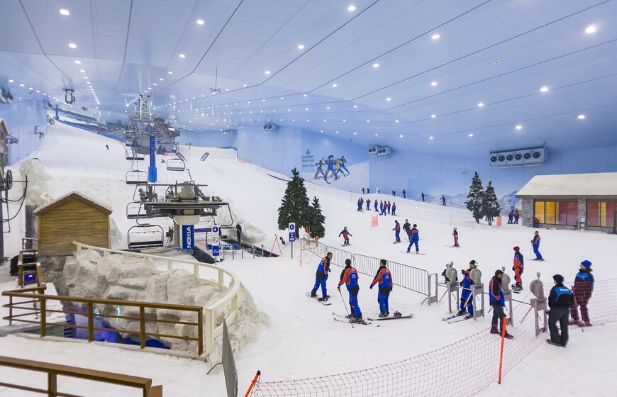 Indoor snow centre in Dubai with chairlifts and real snow and people skiing and snowboarding