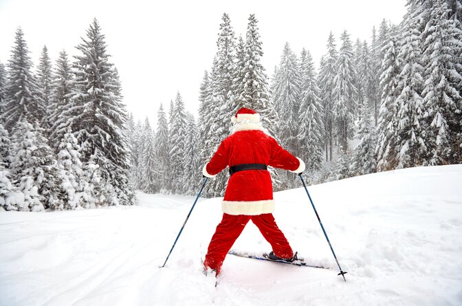 Rear view of Santa skiing snowplough down a snowy piste