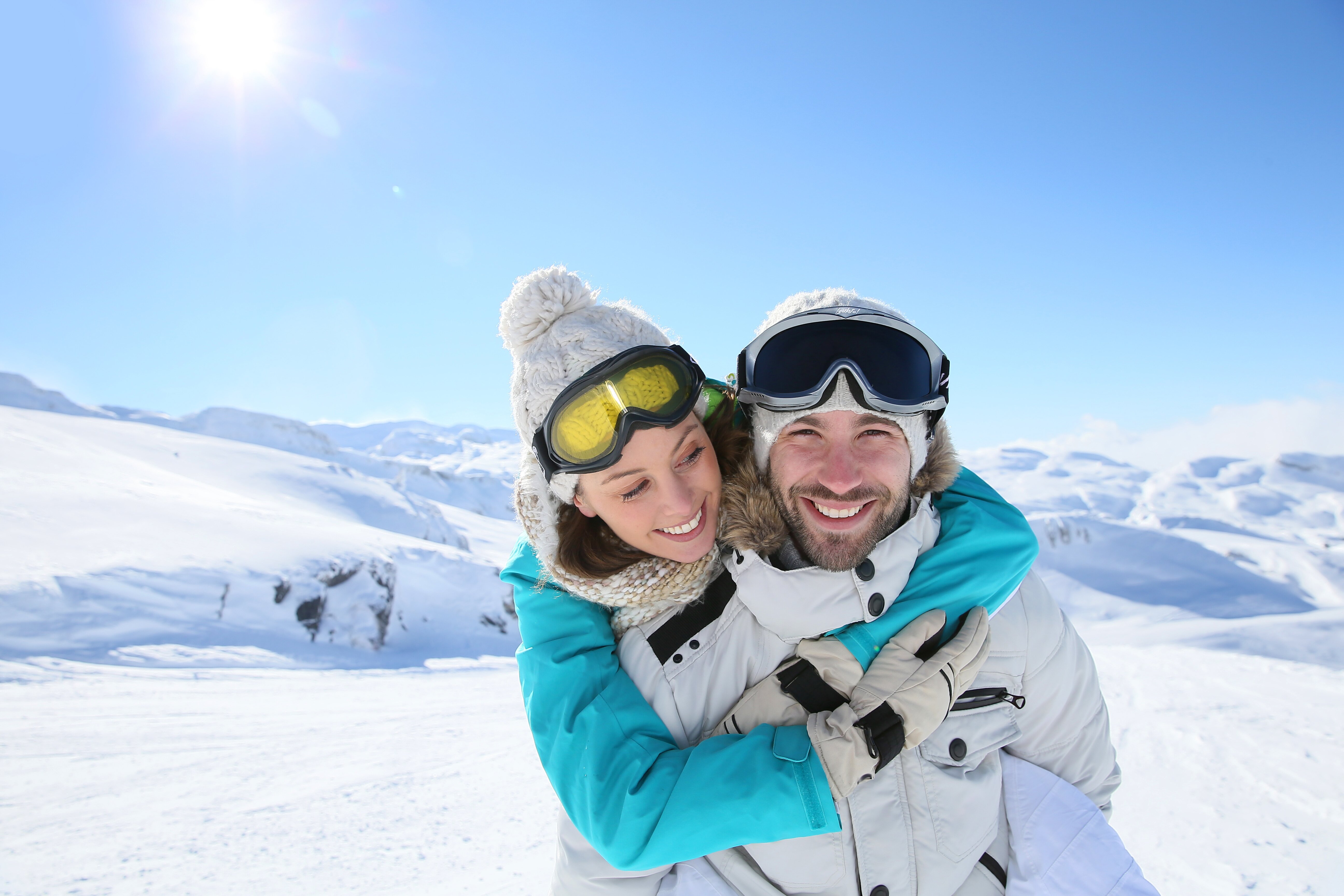 Couple smiling, wearing ski goggles on the piste