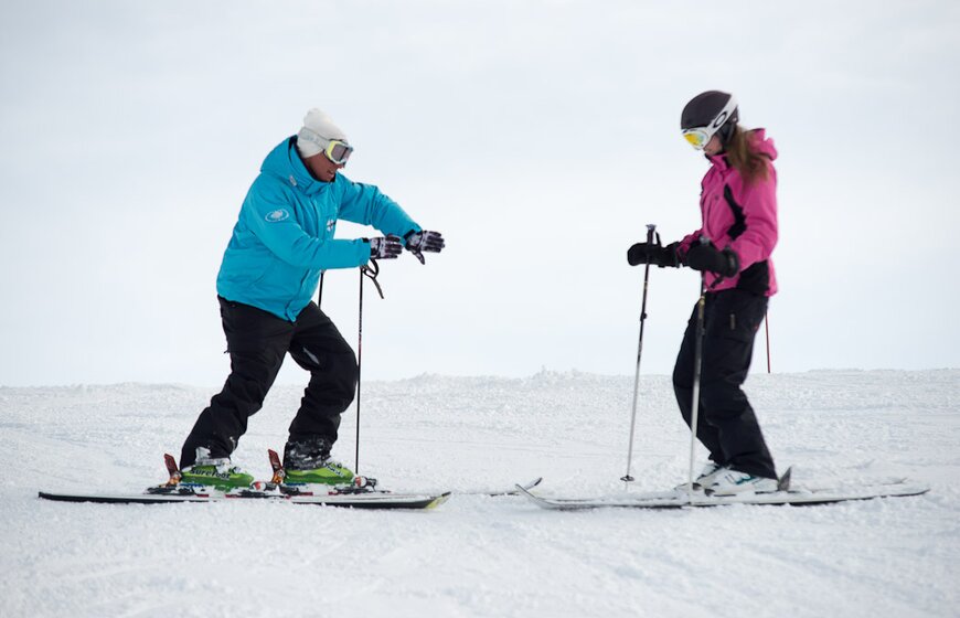 Oxygene ski instructor demonstrating how to turn with hands to female skier