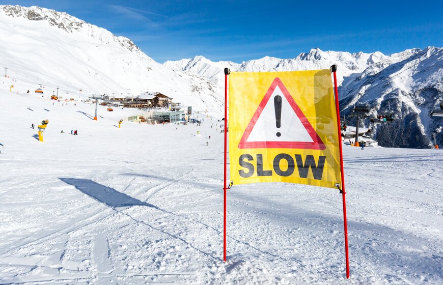 Bright yellow SLOW sign on ski piste