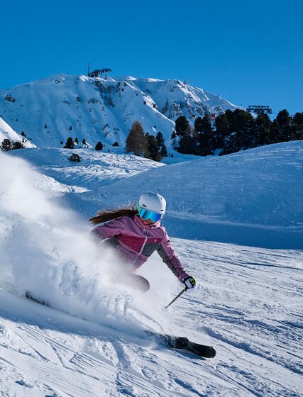 Smiling female skier spraying snow at photographer in La Plagne 