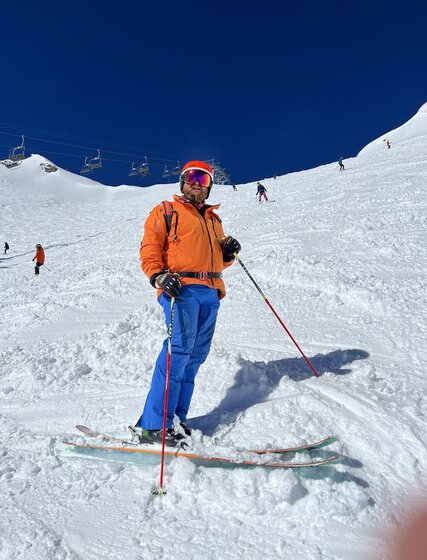 Male skier taking a rest part way down the Swiss Wall ski run on a sunny day