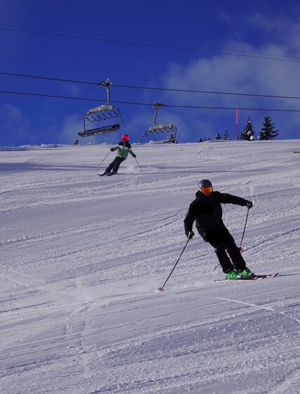 Ski instructor Tom Hudson teaching two young skiers how to carve