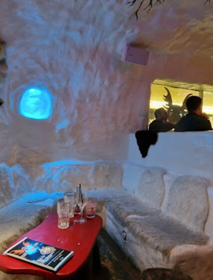 Ice-themed seating area with faux fur seats and real fur hide on the wall in Igloo Igloo bar in La Plagne