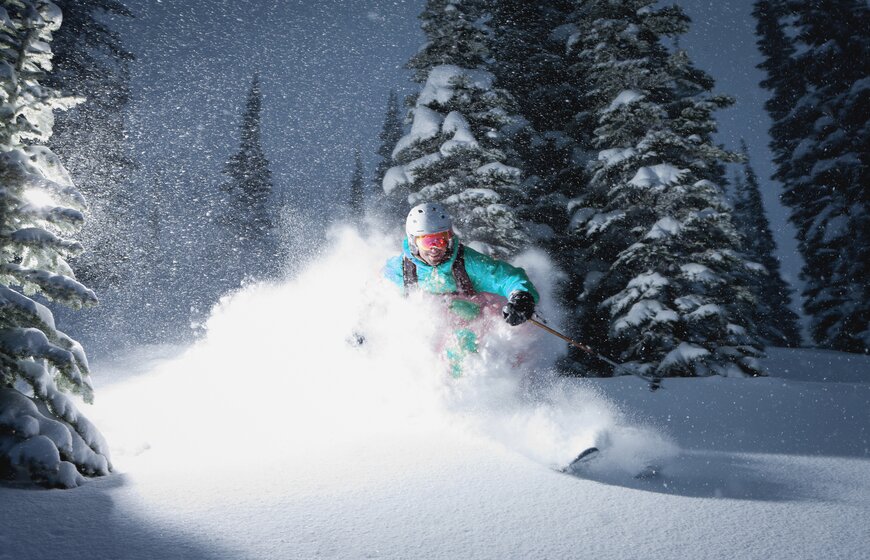 Smiling male skiing powder at night time