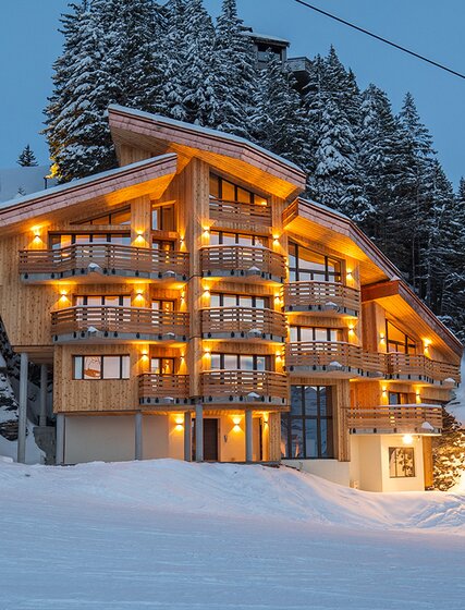 Exterior of modern Chalet Beluga in snowy Avoriaz lit up at nighttime 