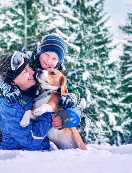 lady and boy in a ski resort with their dog