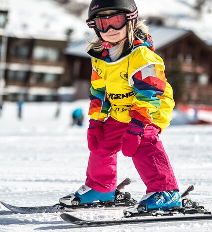 Young girl in bright coloured ski gear learning to ski with Oxygene ski school