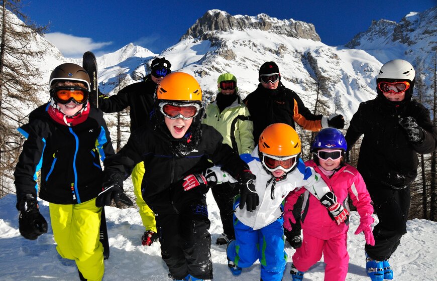 Family group in ski gear smiling and running towards camera