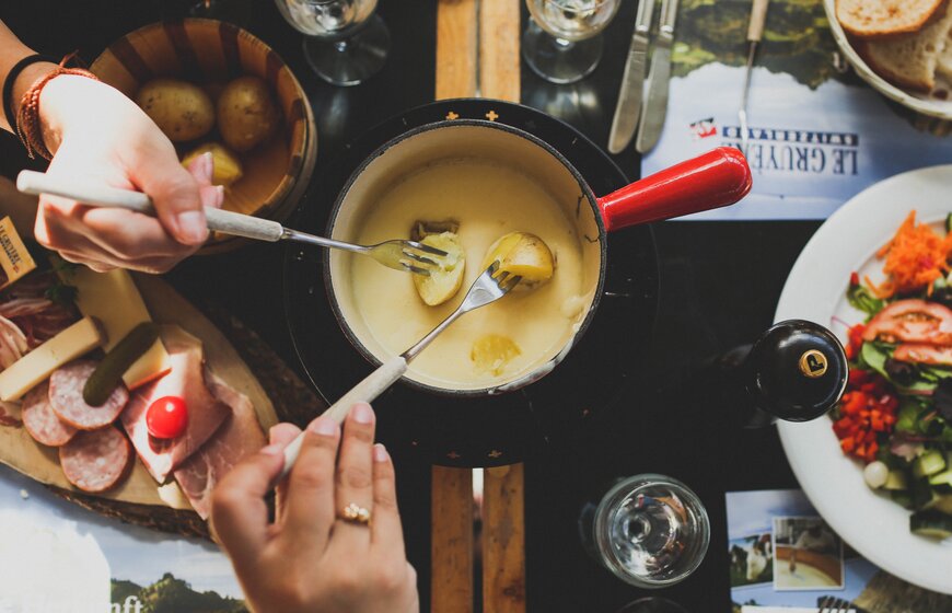 Boiled potatoes being dipped into a cheese fondue