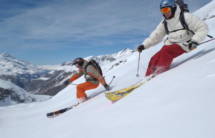 Two male skiers skiing powder in Val d'Isere