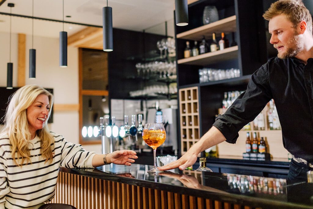 Smiling woman being passed cocktail by barman at Bear Lodge in Les Arcs