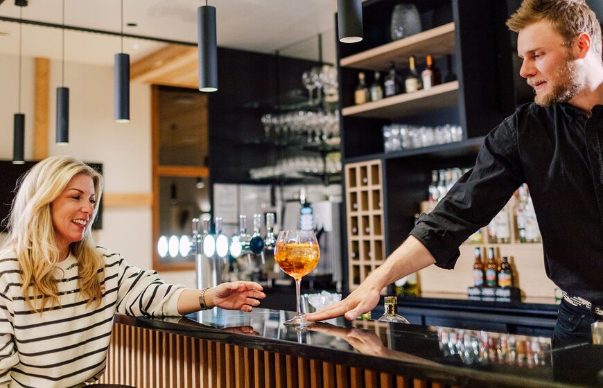 Smiling woman being passed cocktail by barman at Bear Lodge in Les Arcs