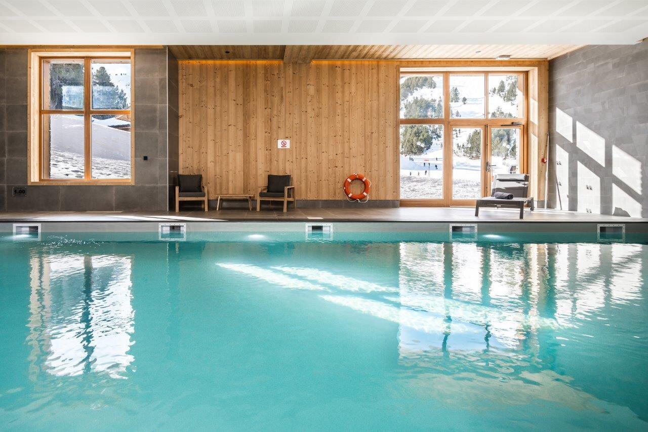 Swimming pool in Bear Lodge, Les Arcs, with views of ski slopes through windows