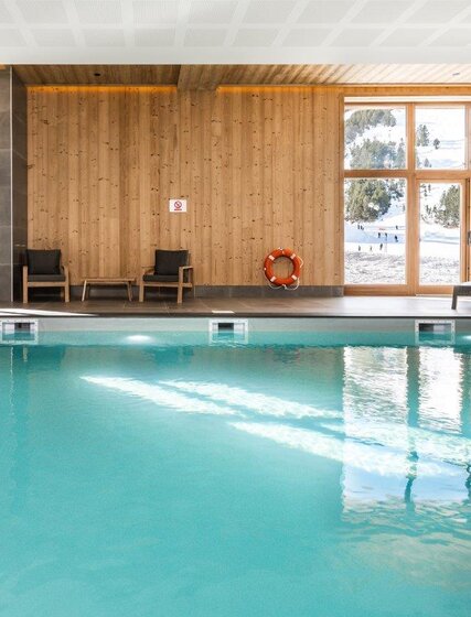 Swimming pool in Bear Lodge, Les Arcs, with views of ski slopes through windows