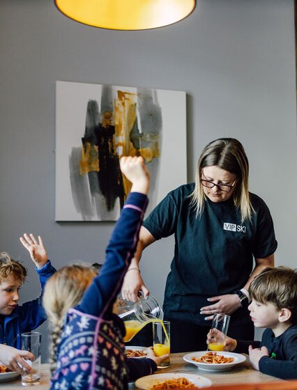 VIP SKI nanny pouring drinks at lunchtime for children in childcare