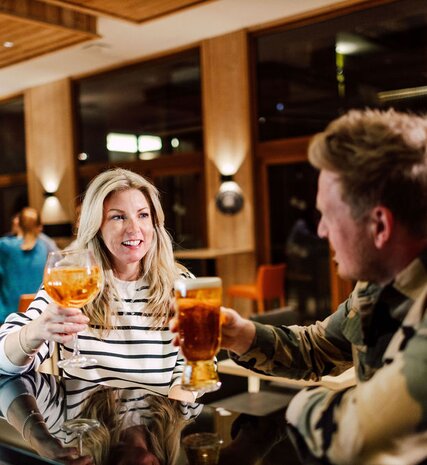 Smiling couple enjoying evening drink at Bear Lodge bar in Arc 1950